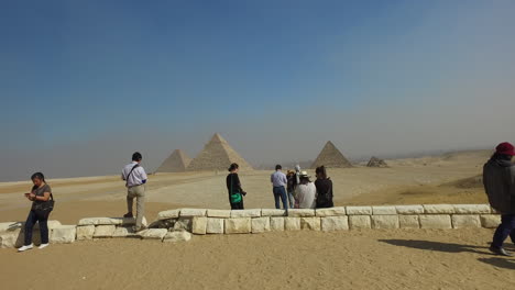 Camera-going-towards-tourists-who-are-taking-pictures-in-front-of-the-pyramids-during-a-sunny-day-in-Giza