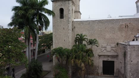 Luftbildkamera,-Die-Sich-Hinter-Einer-Statue-Im-Hidalgo-Park-Erhebt-Und-Sich-über-Dem-Pfarrhaus-Jesus-In-Merida,-Yucatan,-Mexiko-Fortsetzt