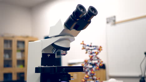 Ein-Mikroskop-In-Einem-Biologie-Forschungslabor-An-Einer-Hochschule-Mit-Einer-DNA-Doppelhelix-Lernfigur-Und-Einem-Whiteboard-Im-Klassenzimmer