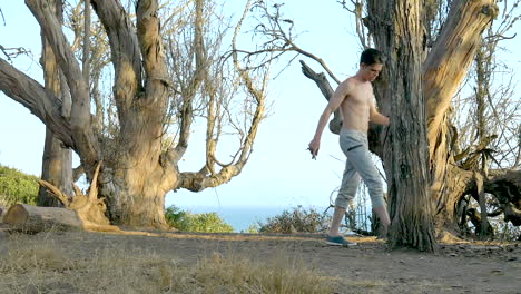 Young-shirtless-man-jogging-in-slow-motion-during-a-workout-on-the-bluffs-overlooking-the-blue-Pacific-ocean-in-Santa-Barbara,-California