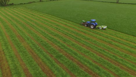Aerial-view-of-a-tractor-cutting-the-grass-in-a-large-green-field
