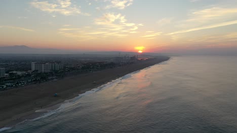 4k-Ariel-drone-shot-of-the-cityscape,-beachfront-hotels,-and-beach-front-homes-at-sunrise-sunset-in-beautiful-Huntington-Beach,-Surf-City-USA-California-as-families-enjoy-their-summer-vacation