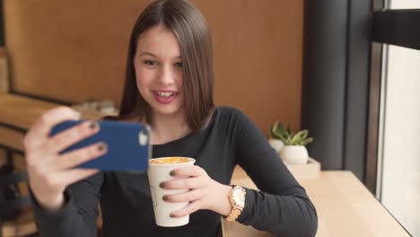 Schönes-Mädchen,-Das-In-Einem-Restaurant-Sitzt-Und-Kaffee-Trinkt,-Während-Es-Auf-Ihrem-Telefon-Per-Video-Chattet