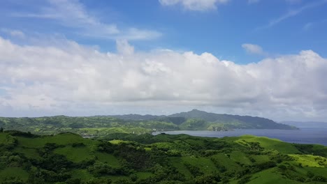 Green-hills-by-the-ocean-below-thick-clouds-in-Batanes,-Philippines---High-view