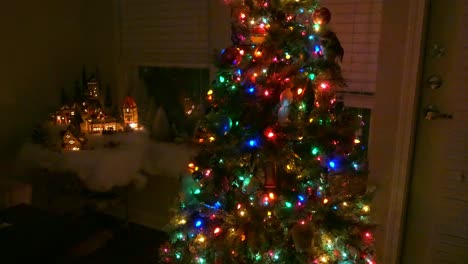 Un-Pueblo-Modelo-En-Navidad-Con-Luces-Navideñas-Y-Un-árbol-Al-Lado-Por-La-Noche