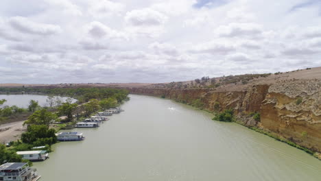 Aerial-shot-flying-over-houseboats-and-incredible-limestone-cliffs-on-the-stunning-Murray-River,-South-Australia