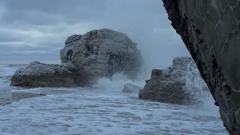 Big-stormy-waves-breaking-against-abandoned-seaside-fortification-building-ruins-at-Karosta-Northern-Forts-in-Liepaja,-slow-motion-wide-shot