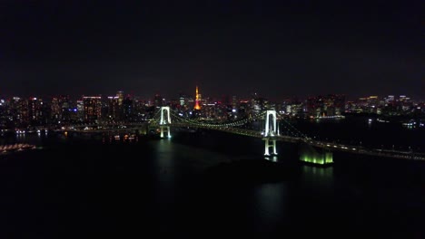 Aerial-view-rising-on-rainbow-bridge-at-night-time-over-water