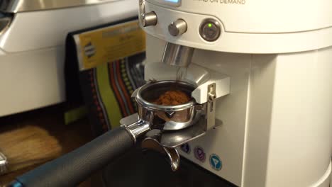 SLOWMO---Professional-female-barista-grinds-fresh-coffee-beans-into-portafilter---close-up