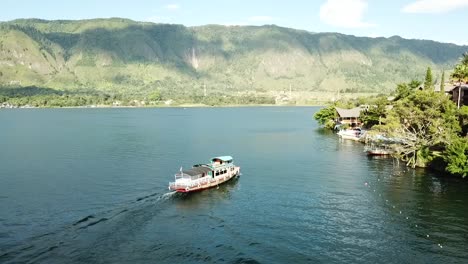 Drone-view-of-small-ferry-docking-at-a-resort-in-Samosir,-Lake-Toba,-Sumatra,-Indonesia