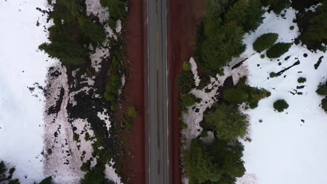 Top-down-view-of-Oregon-mountain-pass-highway,-white-car-traveling-through