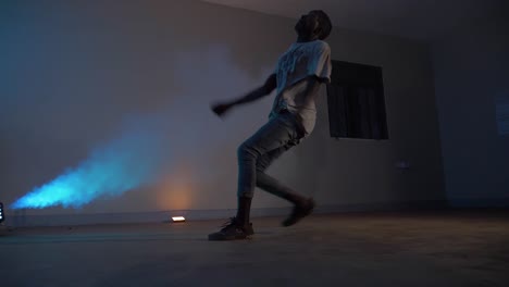 Slow-motion-shot-of-African-youth-doing-a-running-back-flip-in-disco-lights-and-with-blue-smoke-blowing
