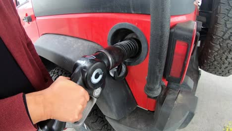Pumpen-Von-Benzin-An-Der-Tankstelle-In-Ein-Rotes-Fahrzeug