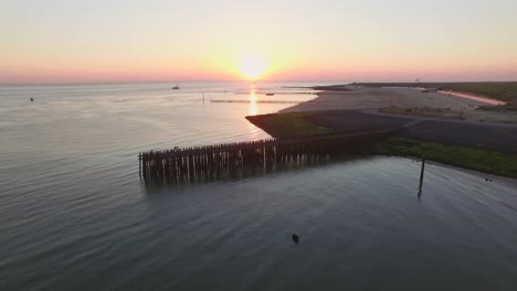 Aerial:-The-pier,-beach-and-lighthouse-during-sunset-near-the-village-Westkapelle,-the-Netherlands