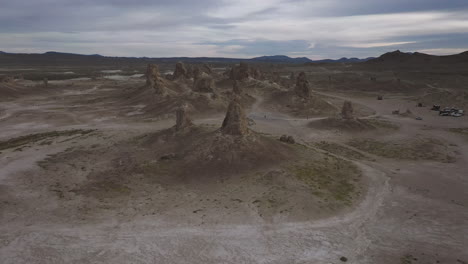 Drone-flying-backwards,-revealing-camp-site-at-Trona-Pinnacles-in-California,-a-location-for-many-movies-and-commercials