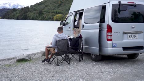 Young-couple-getting-off-their-rv-to-eat-lunch-by-Lake-Wakatipu,-Queenstown,-New-Zealand