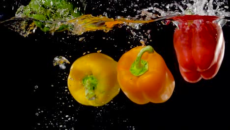 Vibrant-bell-peppers-being-dropped-into-water-in-slow-motion