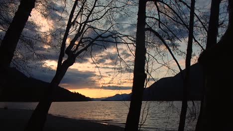 Inspiration-Sonnenuntergang-Am-See-Mit-Bergen-Im-Hintergrund-Und-Bäumen-Im-Vordergrund