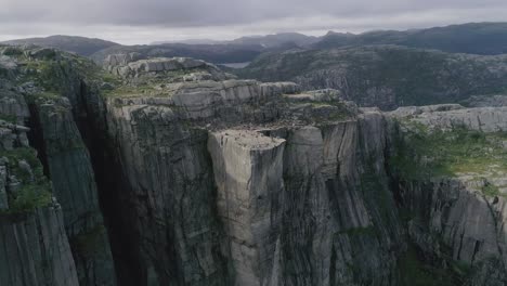Aerial-Slomo-flying-towards-the-Preikestolen,-Norway,-with-Tourists-on-top-Walking-and-Photographing-the-Scenery