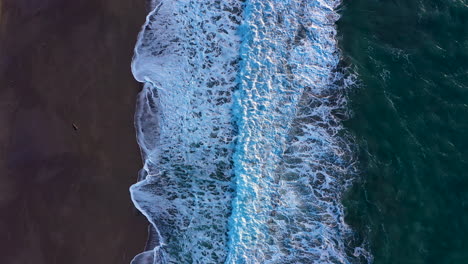 Drone-top-view-of-turquoise-ocean-waves-crashing-ashore