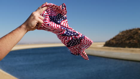 A-red-white-and-blue-American-flag-bandana-flying-in-the-strong-wind-in-slow-motion-with-the-California-Aqueduct-in-the-background
