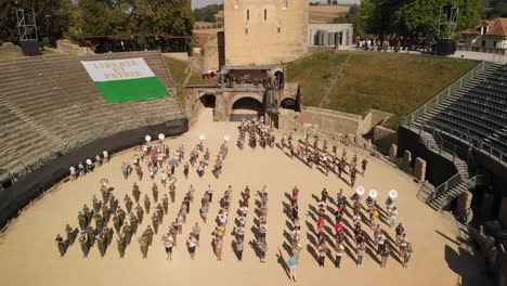 Aerial-drone-shot-orbiting-around-the-arena-in-Avenches-Switzerland-with-musicians-marching-out-in-formation