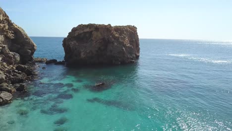 Tilt-up-shot-of-a-big-rock-close-the-coast-in-the-mediterranean-sea