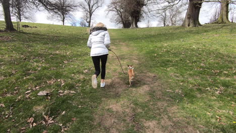 blonde-pretty-woman-runs-up-hill-with-dog