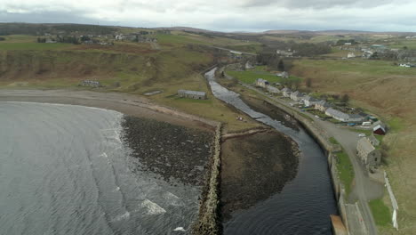 Aerial-view-heading-inland-towards-Dunbeath-town-across-the-river-mouth,-Caithness,-Scotland
