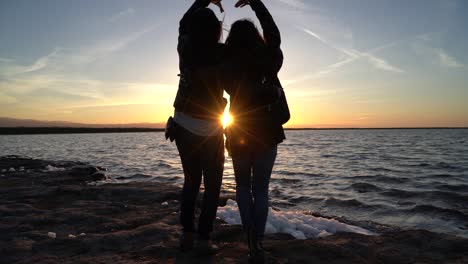 Sisters-making-a-heart-together-as-they-enjoy-a-gorgeous-sunset-falling-below-the-horizon-of-giant-salt-pond