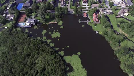 A-topdown-drone-shot-panning-forward-and-up,-over-a-green-island-with-water,-in-the-Netherlands