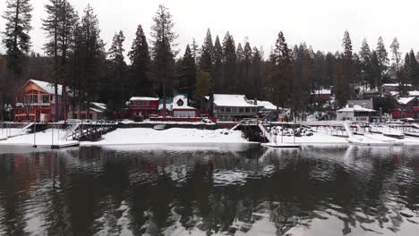Pan-right-of-shining-lake-in-the-winter,-houses-and-docks-on-snowy-shore