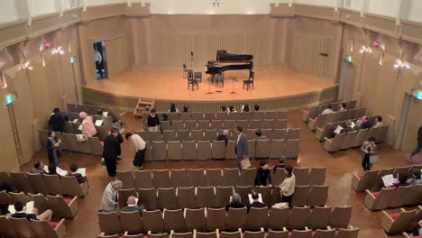 Japanese-spectators-entrance-and-sitting-at-a-concert-hall-with-a-program-in-their-hands