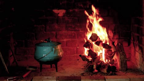 Fuego-Crepitante-En-La-Chimenea-Con-Una-Olla-Lista-Para-Cocinar-Al-Costado