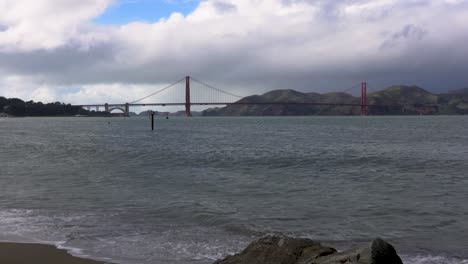 Gewitterwolken-Rollen-über-Die-Golden-Gate-Bridge,-Während-Wellen-An-Den-Strand-In-San-Francisco-Krachen
