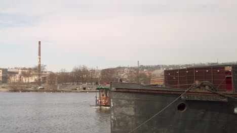A-vintage-ferry-on-the-Vltava-River-emerges-into-view-from-around-a-corner-in-Prague,-Czech-Republic