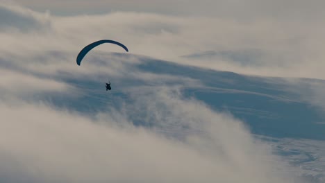 Gleitschirm-Erschossen-Gegen-Das-Licht-Mit-Schneebedeckten-Hügeln-Und-Wolken-Im-Hintergrund,-Cumbria-Uk