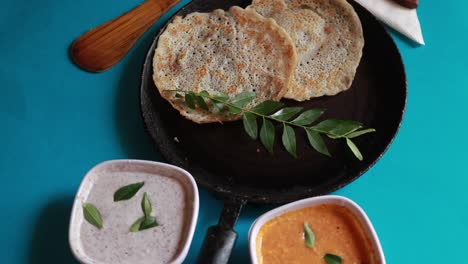 Rotating-South-Indian-food-set-dosa-with-curry-and-chutney-on-blue-background-