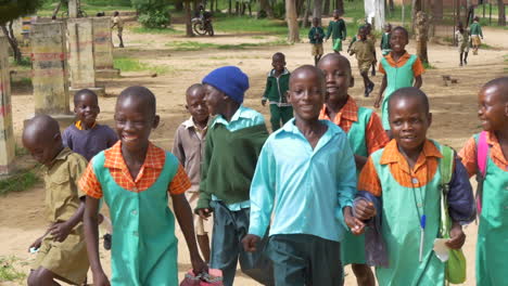 Un-Grupo-De-Niños-De-Zimbabue-Caminan-Alegremente-Hacia-La-Cámara-Mientras-Están-Fuera-De-Su-Escuela,-Movimiento-De-Cámara-Lenta