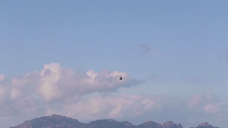 A-far-helicopter-fly-away-towards-mountains