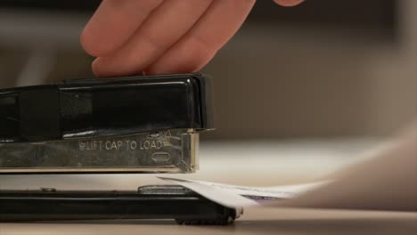Side-view-of-a-black-stapler-stapling-some-paper-together-in-really-slow-motion