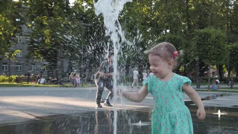 Little-toddler-girl-plays-with-water-fountain-in-the-center-of-Vilnius,-the-capital-of-Lithuania