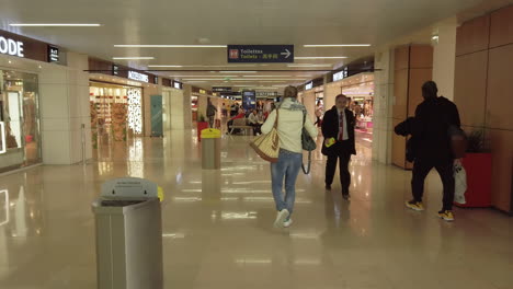 Following-passengers-in-the-interior-of-Orly-airport-on-their-way-to-boarding-and-passing-in-front-of-the-duty-free-shops