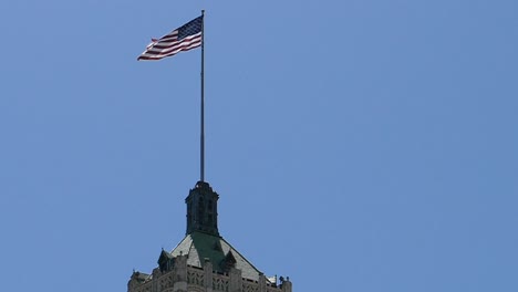 close-up-camera-pulling-out-from-flag-waving-in-the-wind-on-top-of-government-building