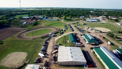 Aerial-push-in-on-equestrian-center-grounds-including-dirt-track,-metal-builds,-cars,-trucks,-and-trailers,-Kansas,-Missouri-Concept:-rural,-equestrian,-midwest