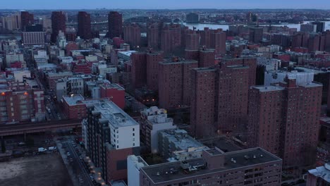 Solemn-and-slow-drone-approach-of-housing-projects-in-New-York-City's-Harlem-neighborhood-at-sunset-blue-hour