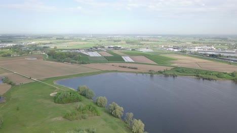 Aerial-footage-of-the-flat-landscape-with-the-fields-and-a-big-lake-in-Holland