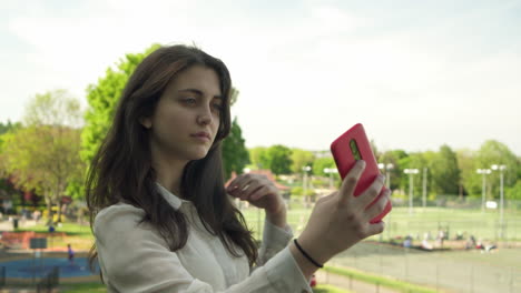 Junge-Italienische-Frau-Mit-Smartphone,-Die-Sich-Im-Freien-In-Einem-Park-In-London-Selbst-Macht