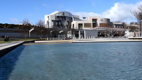 The-Scottish-Parliament-building-viewed-over-pool-of-water-on-a-sunny-day