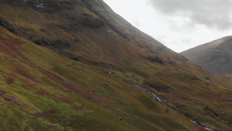 Flying-toward-a-stream-making-its-way-downhill-along-an-epic-landscape-in-the-Glencoe-area-of-Scotland